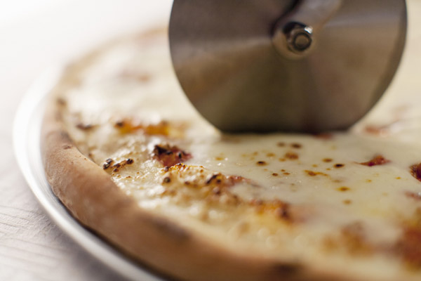 Close up of cutter slicing pizza